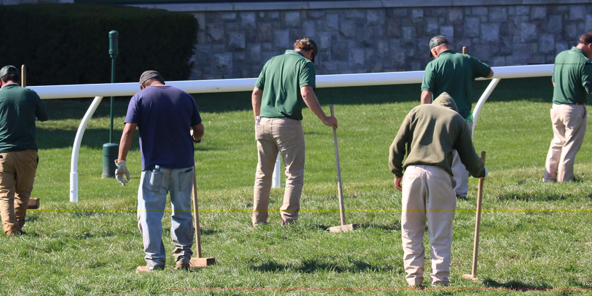 An action shot of Keenlandsscape team members tamping down turf divots.